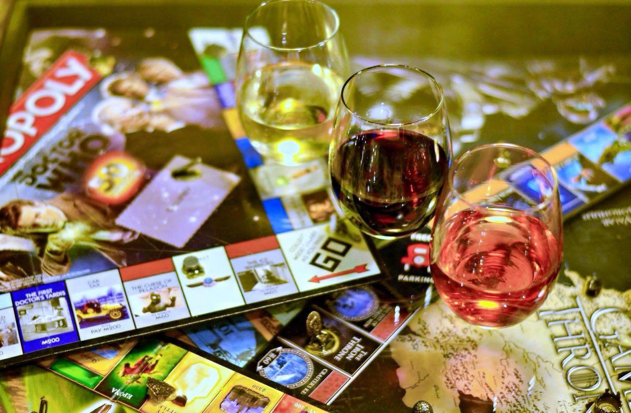 three glasses of wine resting on a Monopoly board