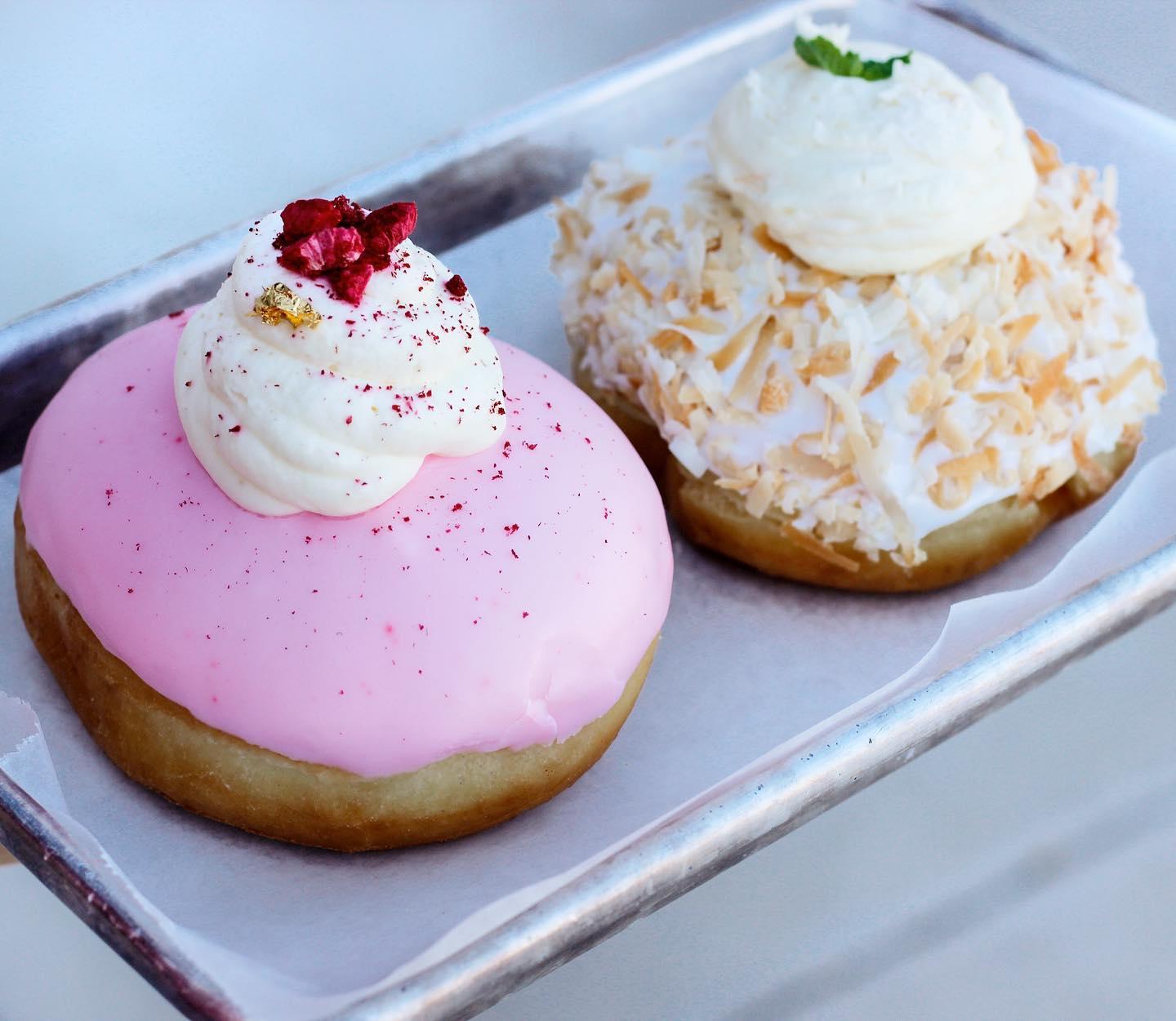 Two frosted donuts, one pink and the other white with sprinkles.