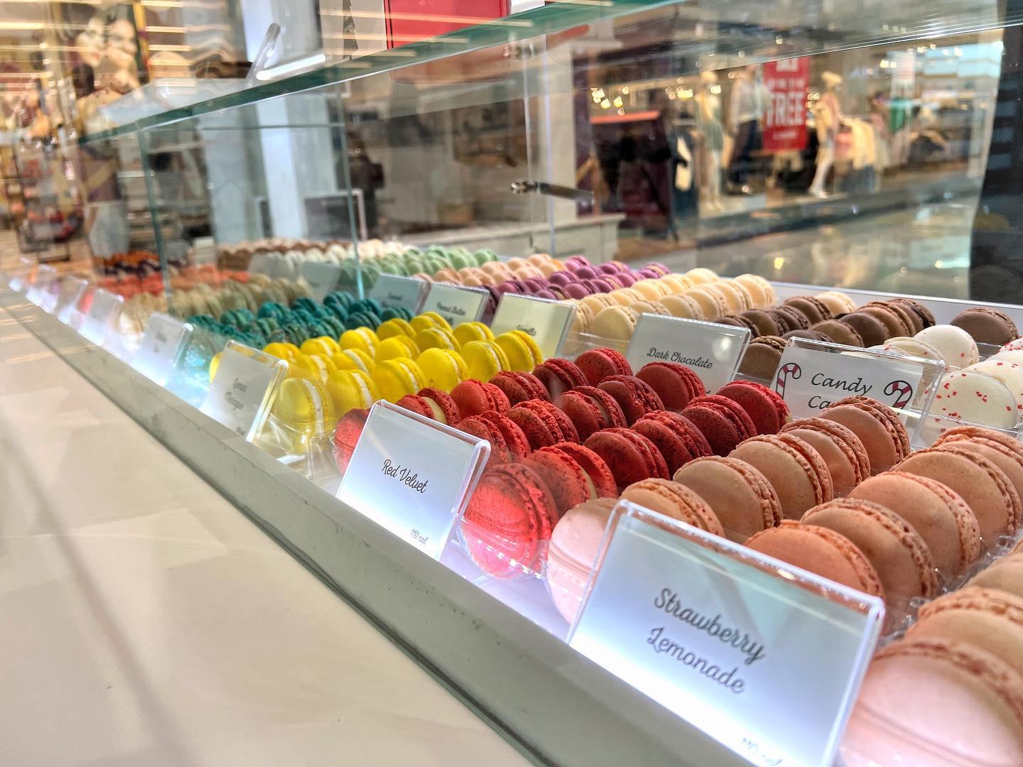 An assortment of colorful macaron pasties in a glass case.
