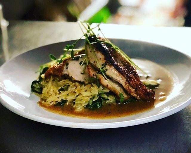 A pork dish on top of pureed vegetables with sauce.