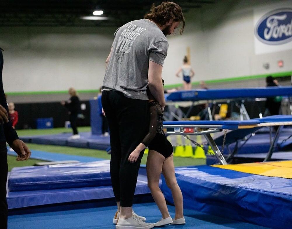 A coach hugs a young gymnast during a competition.