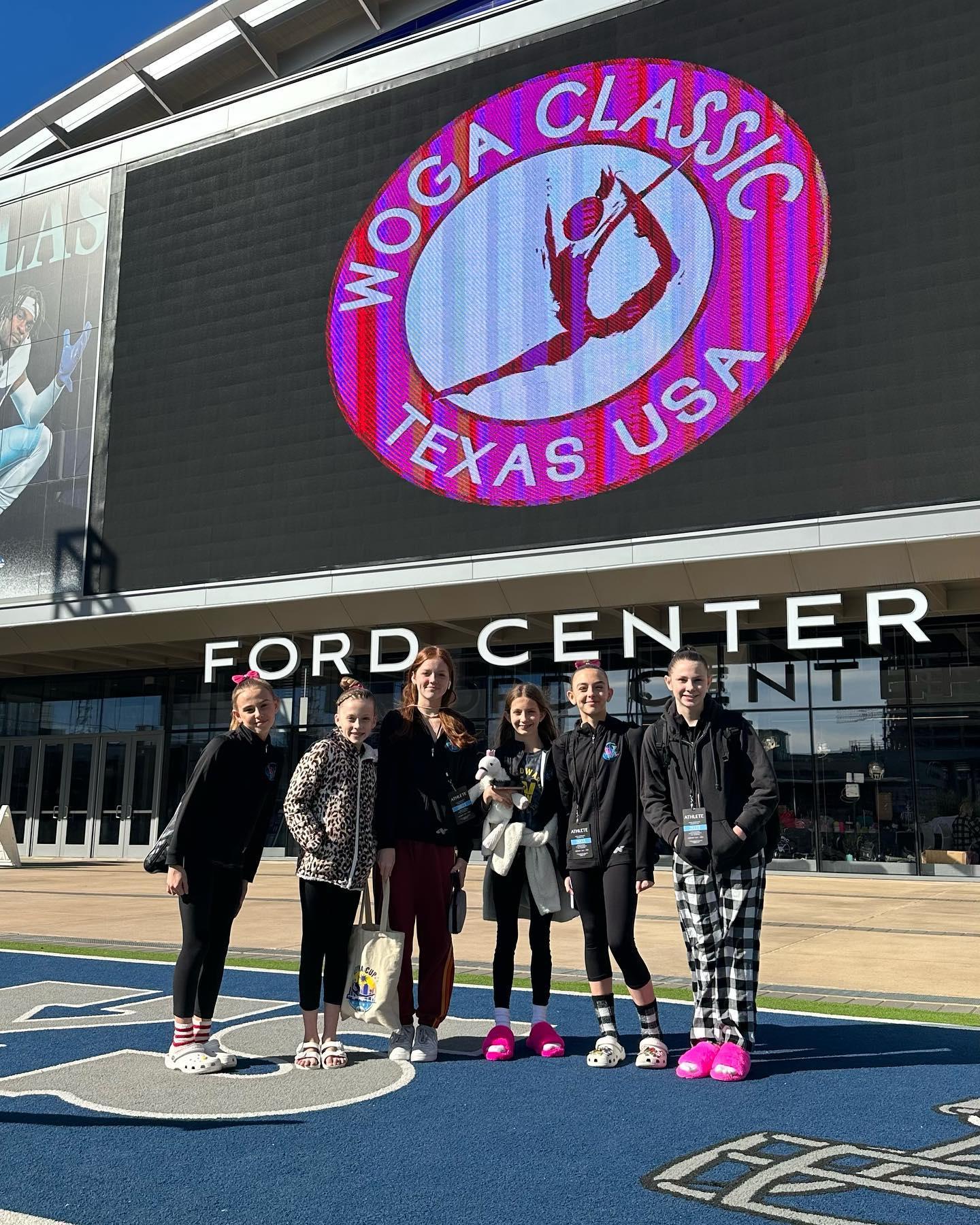 A group of gymnasts pose outside of the Ford Center.