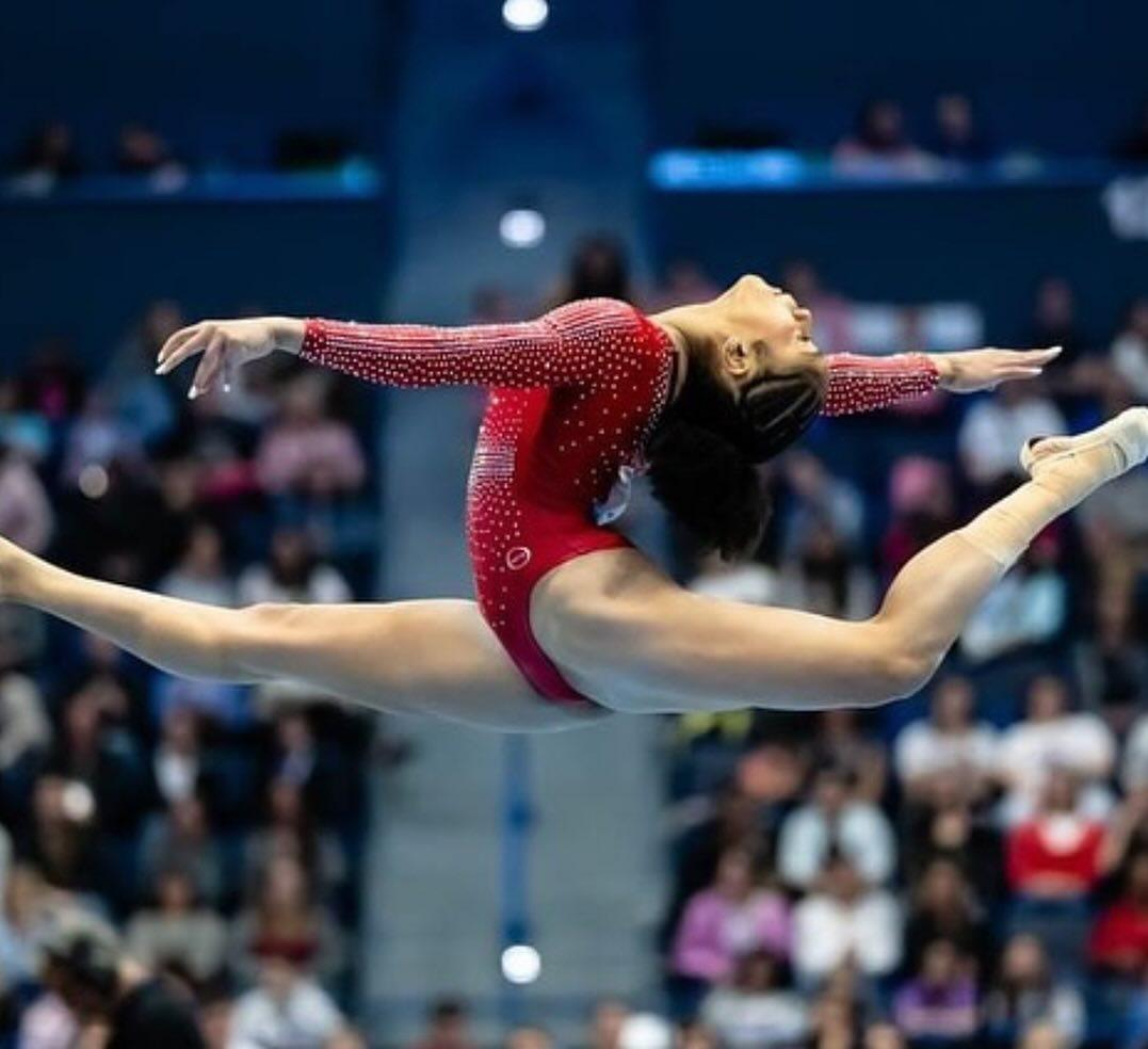 A gymnast jumps high during a competition.