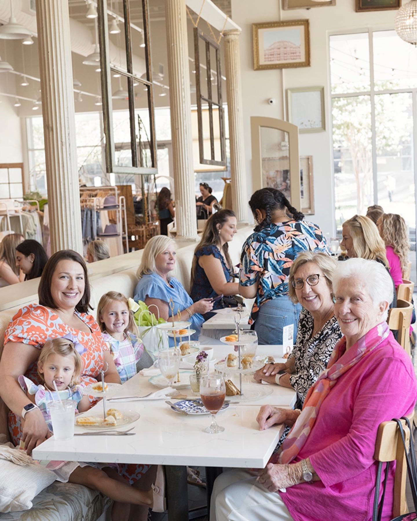A multigenerational family sitting at a large restaurant table smile for a photo.