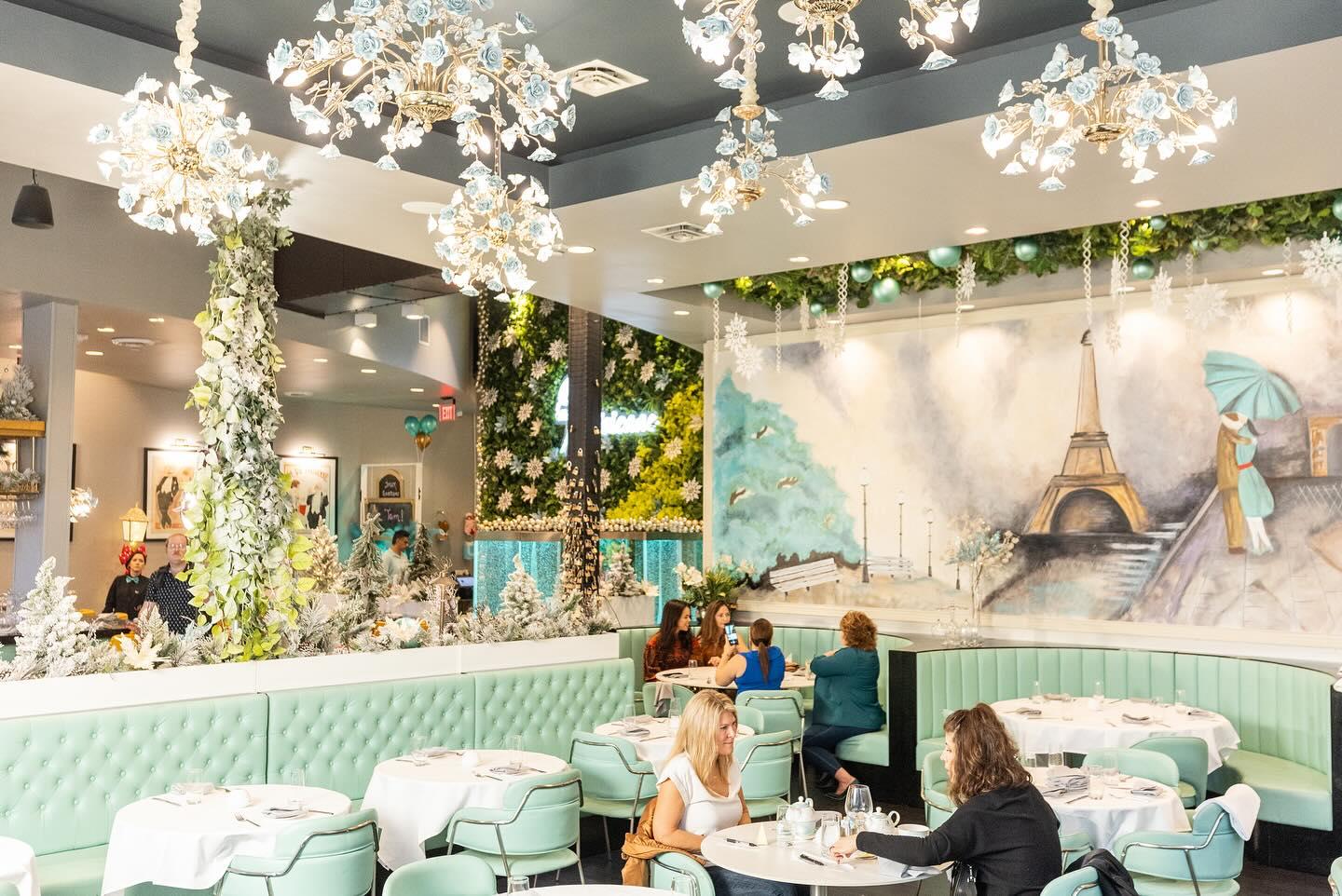 The interior of a restaurant with a large hand painted mural of the Eiffel Tower.