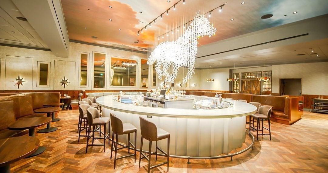 The interior of a restaurant with a grand chandelier shaped like a horse over the bar.