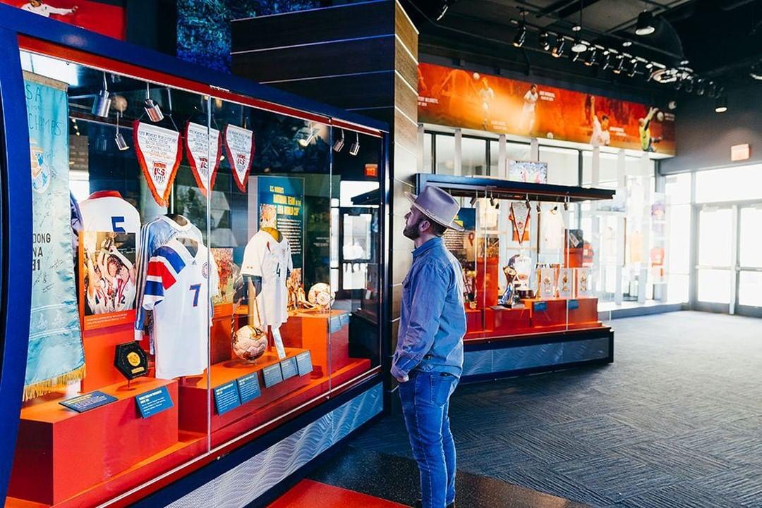 A man wearing a cowboy hat looks at a Dallas Cowboys museum exhibit.