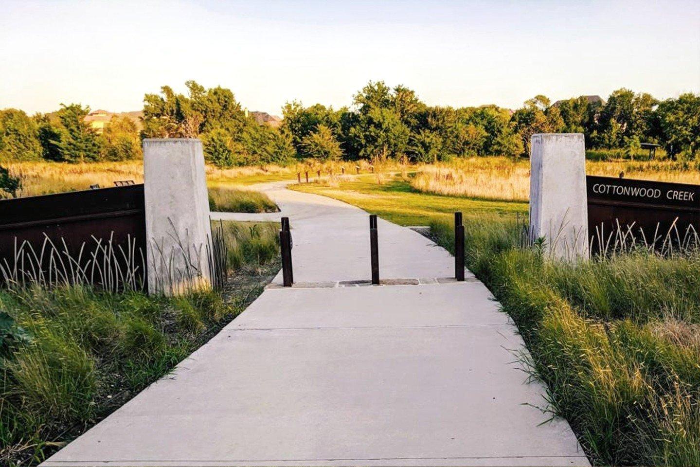 The paved walk way entrance to a park.