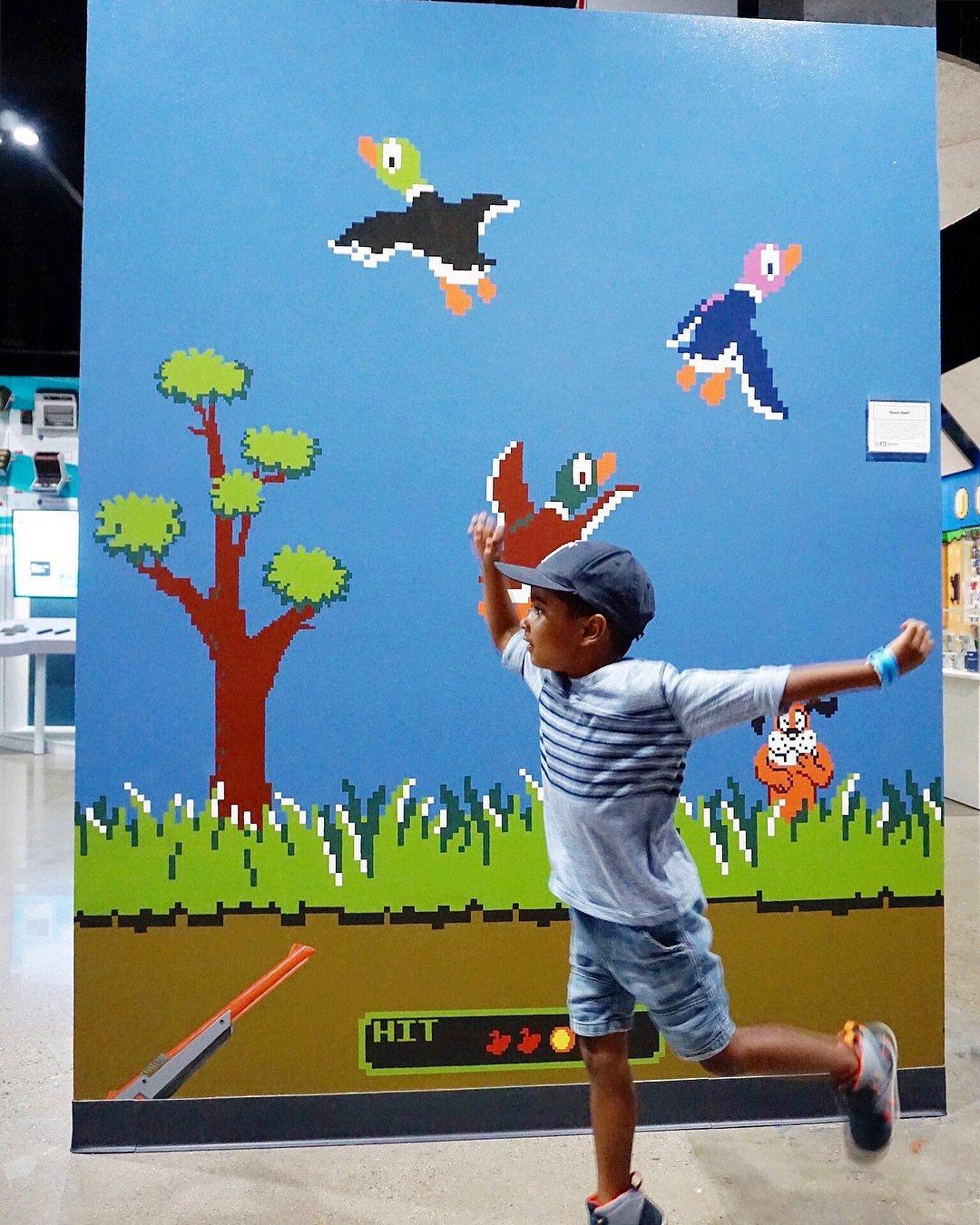 A young boy runs in front of a mural on a wall.