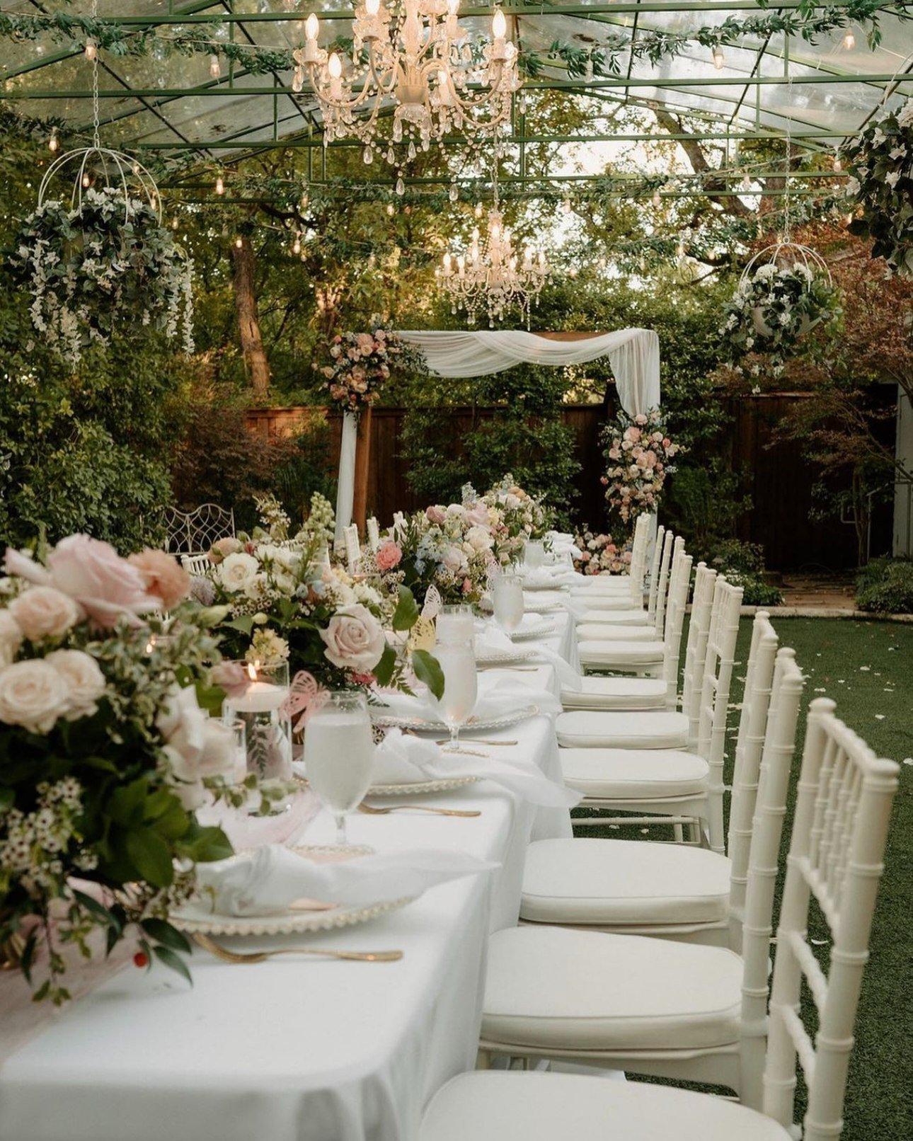 A banquet table set for a wedding with white linens and green floral table decorations.