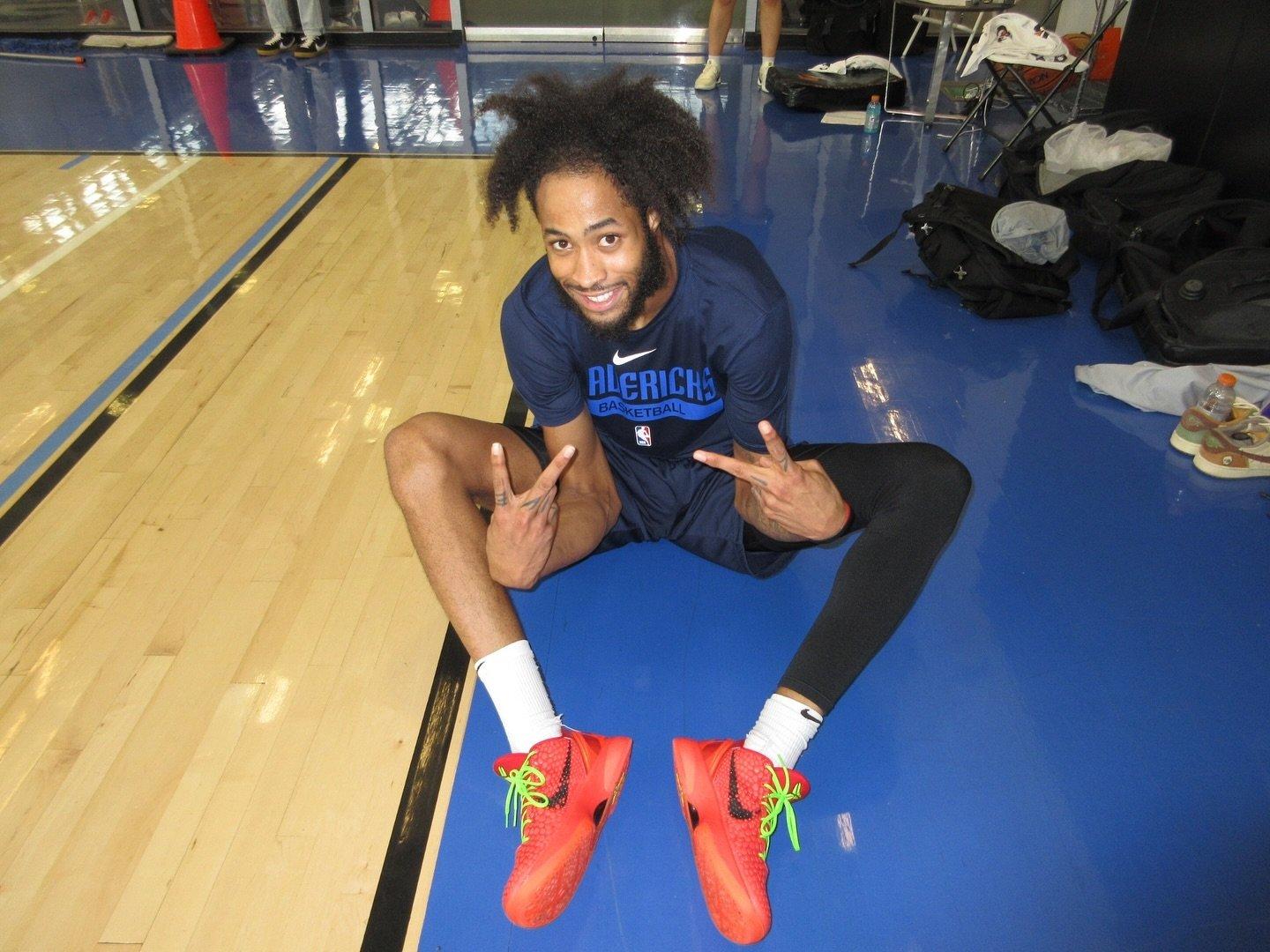 A basketball player sitting on the floor giving peace signs
