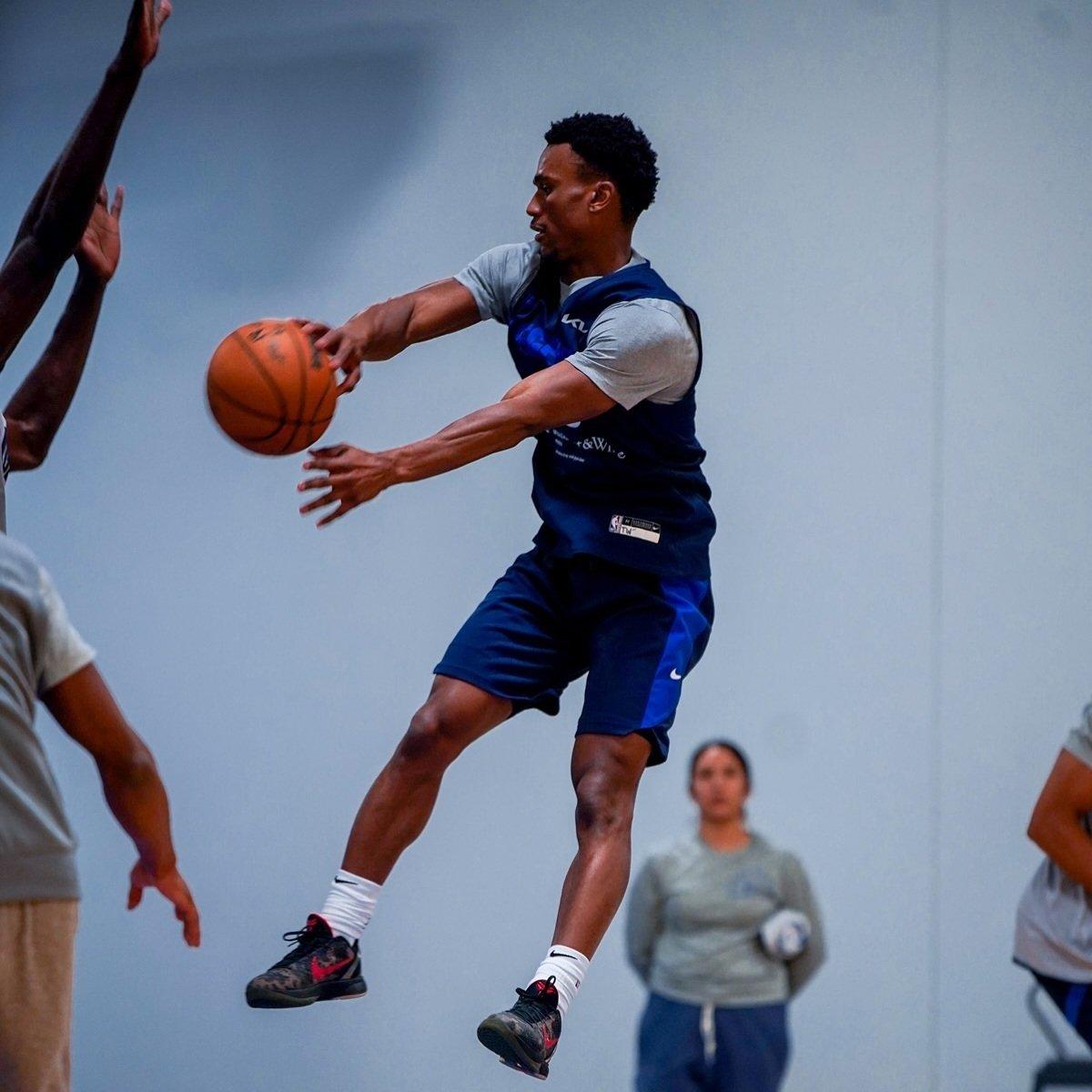 A basketball player mid air throwing the ball to another player