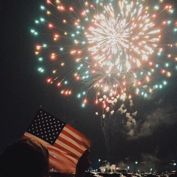 the American flag in front of blue and white fire works