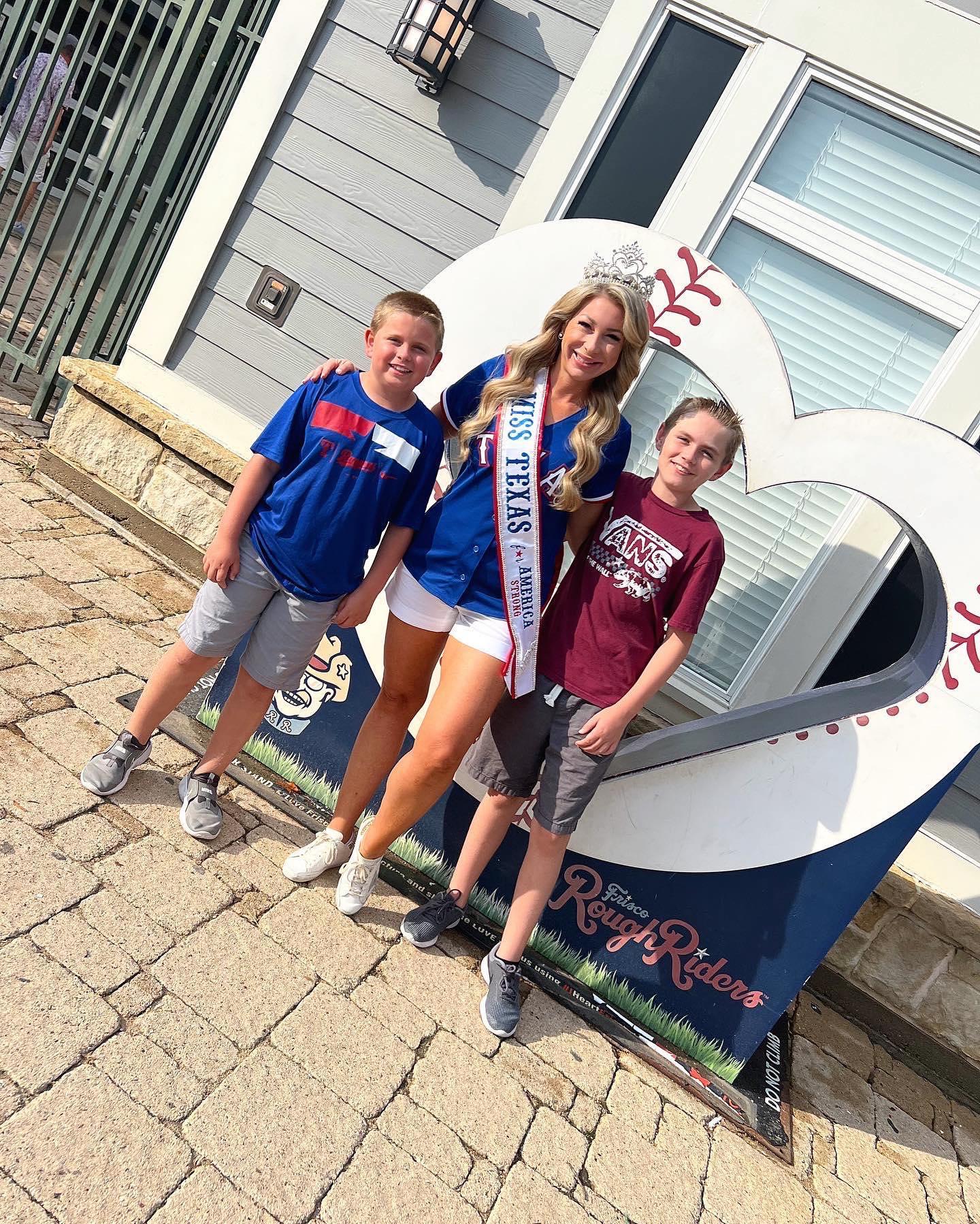 Miss Texas taking a photo with fans in front of a heart sculpture