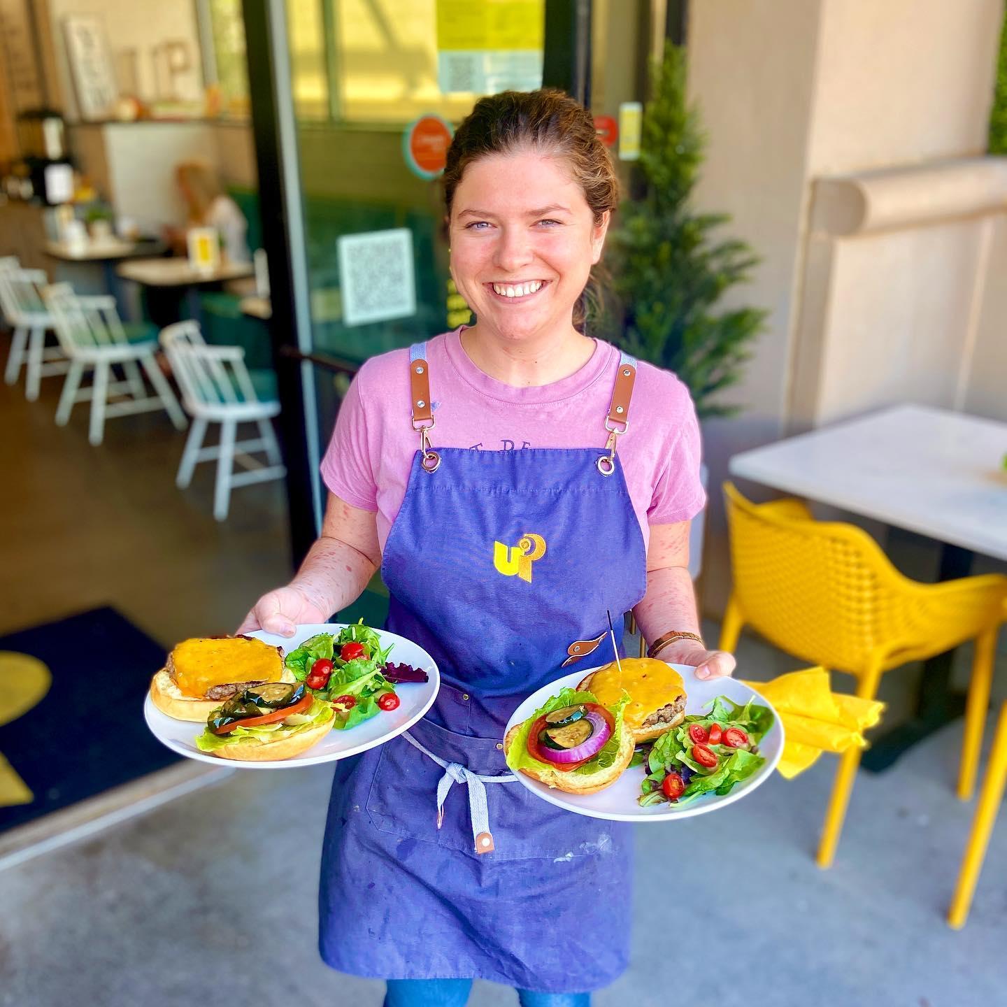 a woman in an apron bringing food to a table