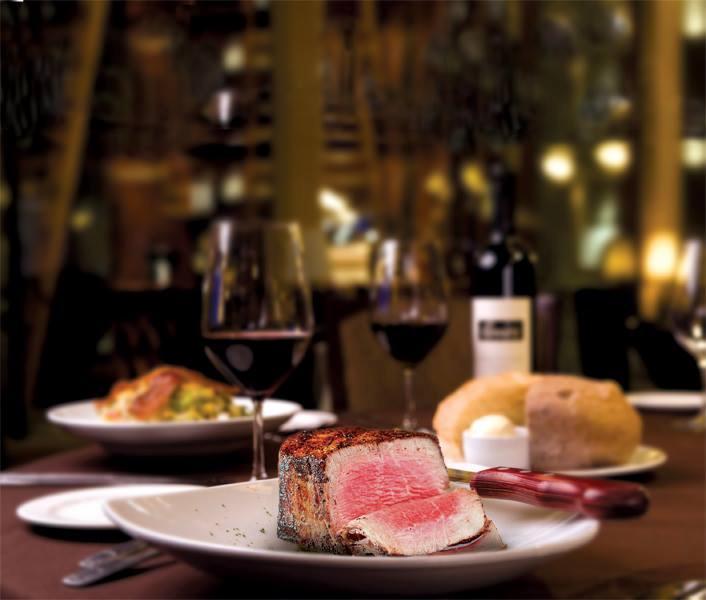 a table set for dinner, in the forefront there is a piece of steak cut showing the pink