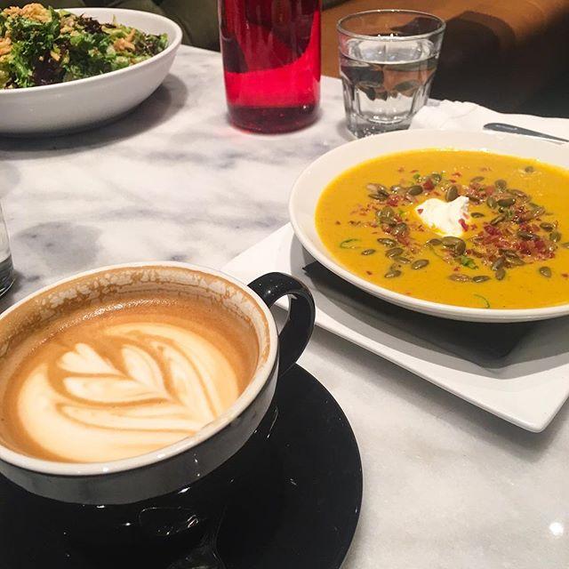 a latte and bowl of soup on a stone table
