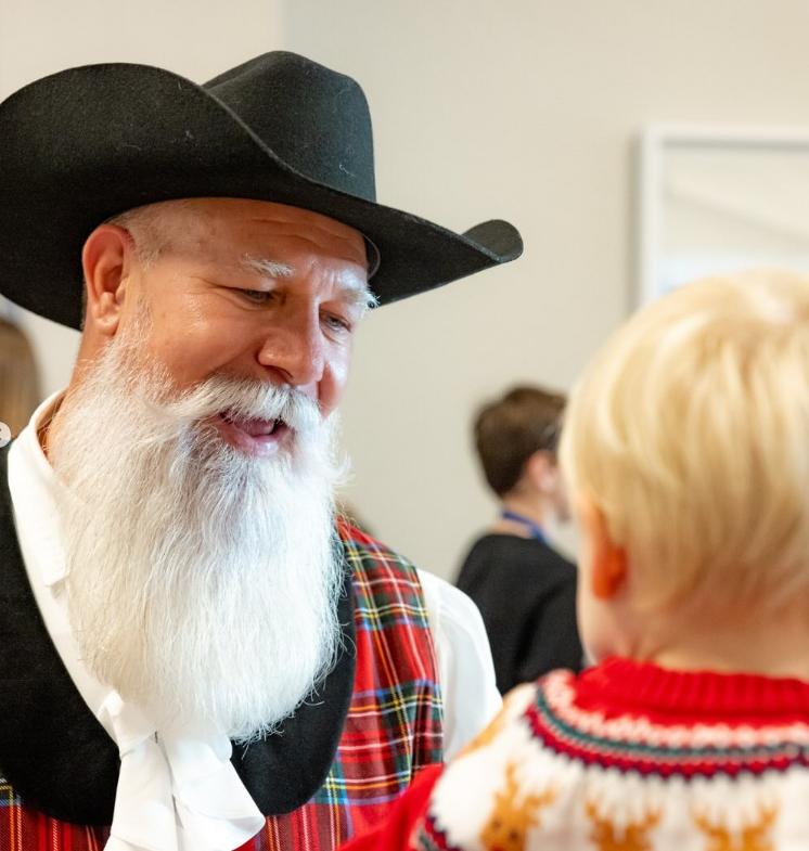 a little boy talking to a man in a cowboy hat and large white beard