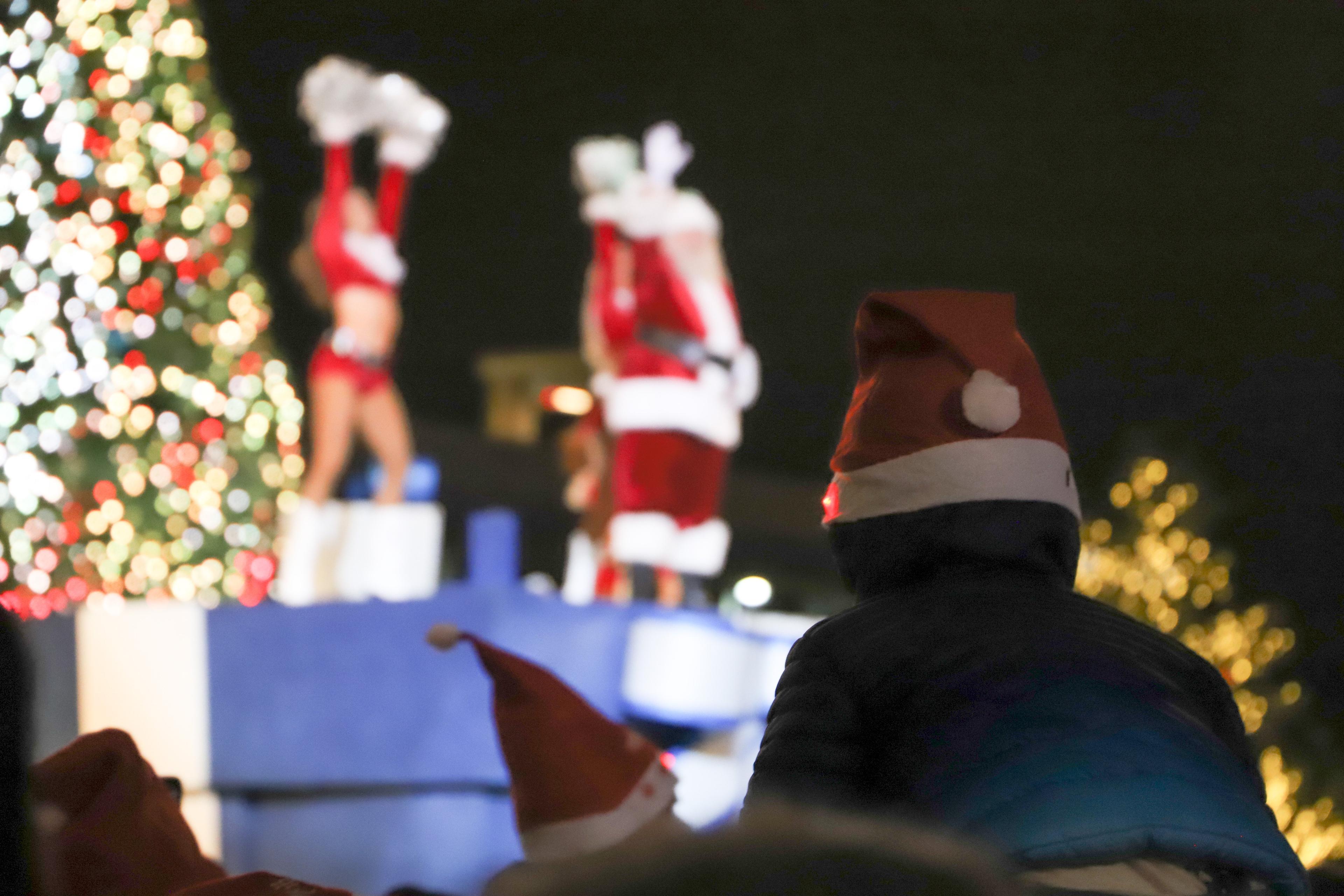 A little kid on his parent's shoulders watching santa
