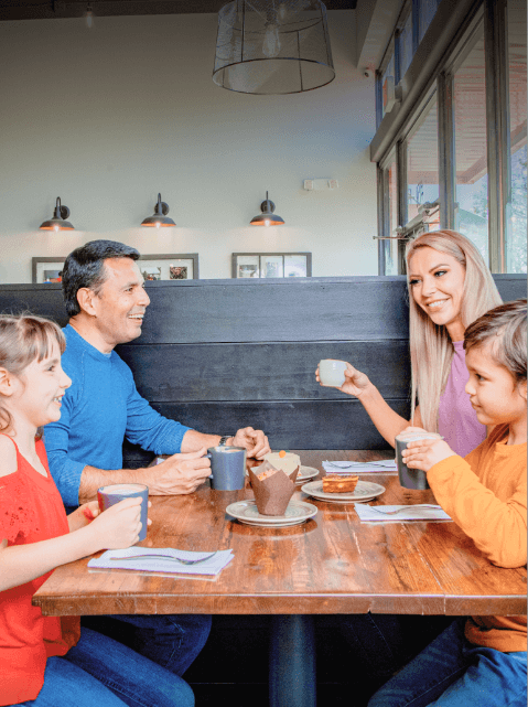 A family drinking hot beverages in a booth