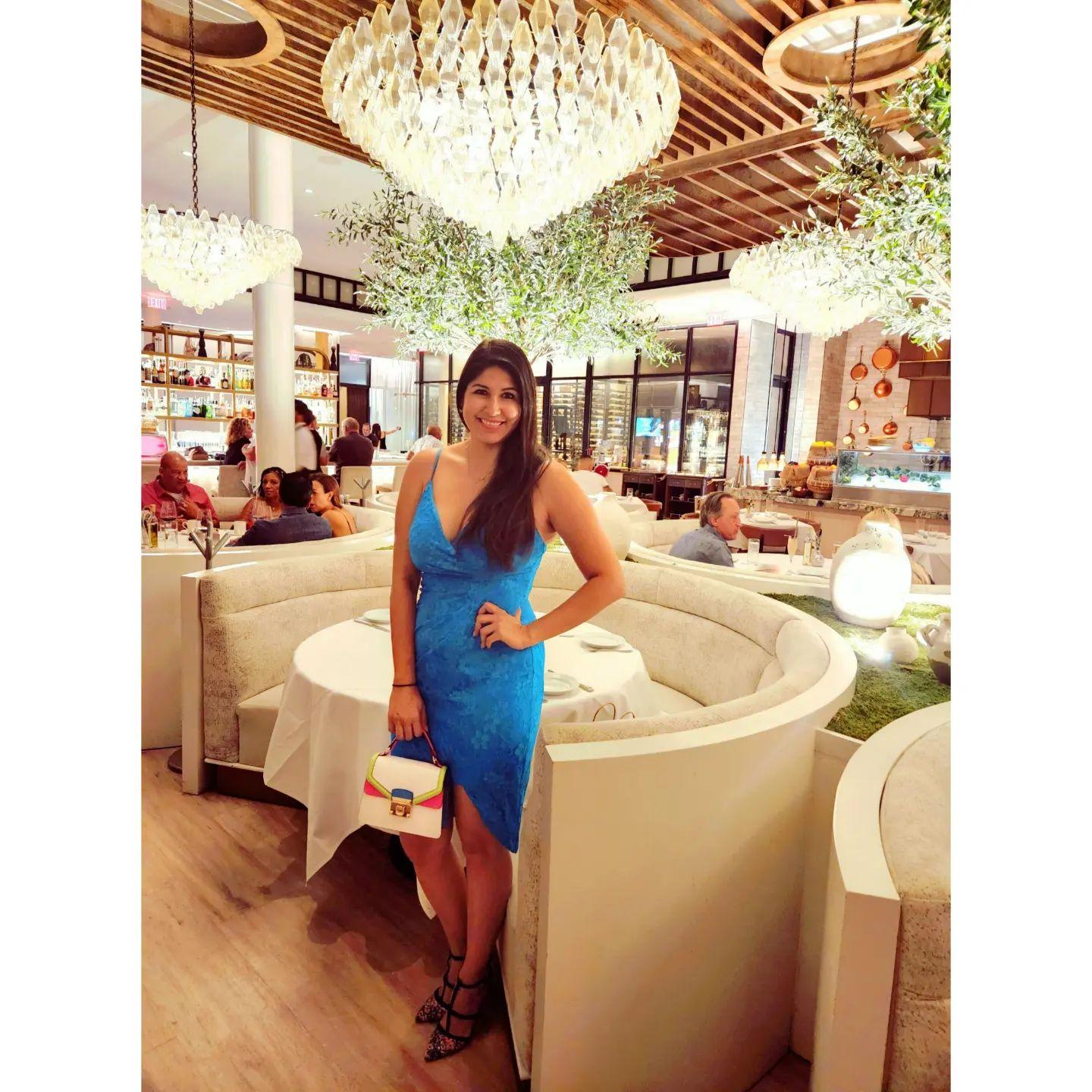 a woman in a blue dress posing next to a booth in a restaurant