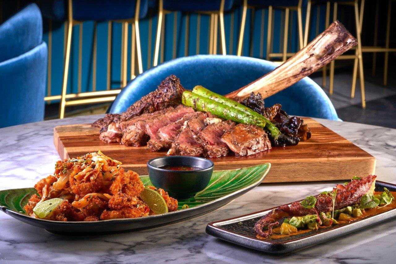 a table with plates of various food including ribs and octopus