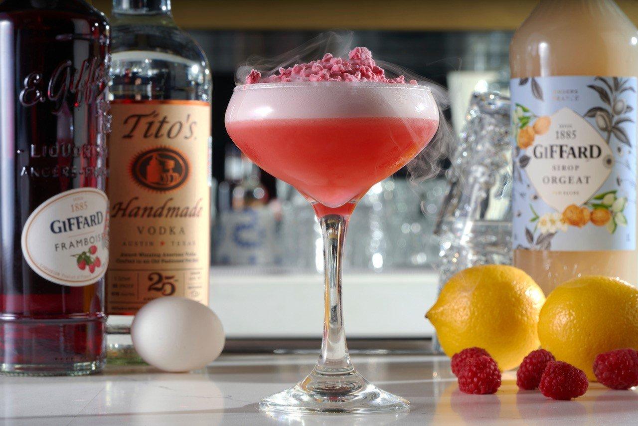 A cocktail with raspberry garnish
