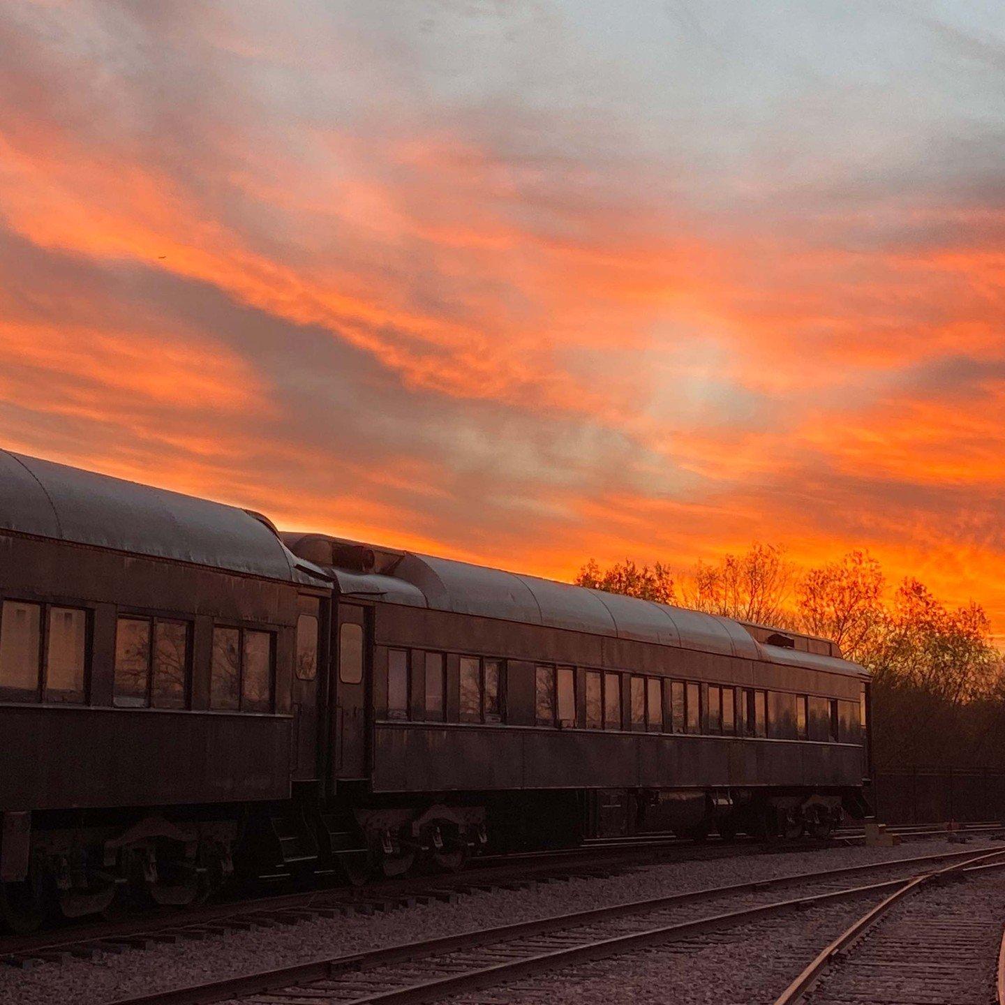 a train on the tracks with the sun setting in the background