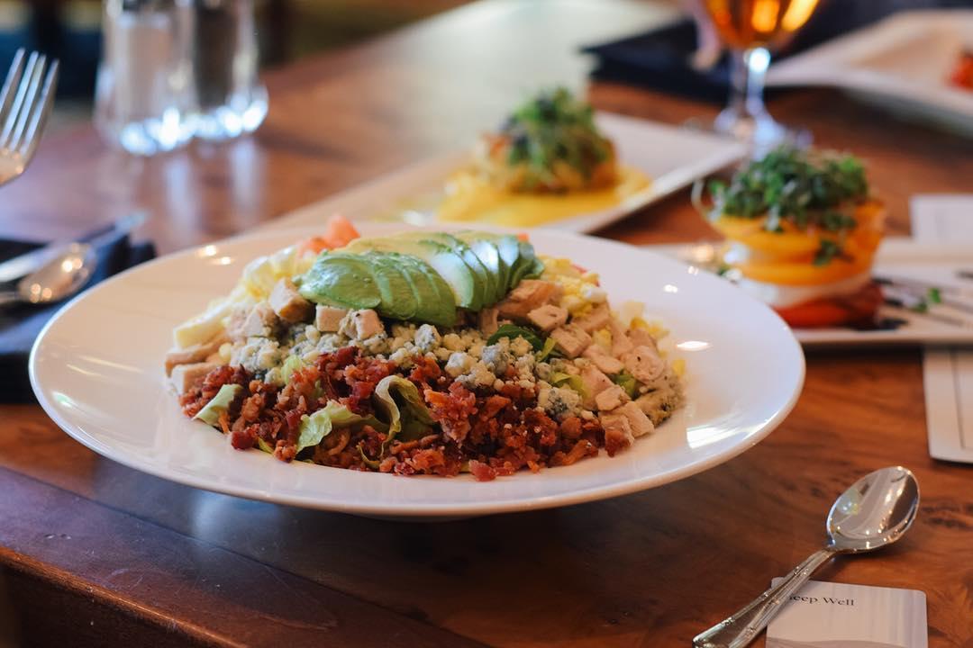 A large bowl of salad topped with avocado