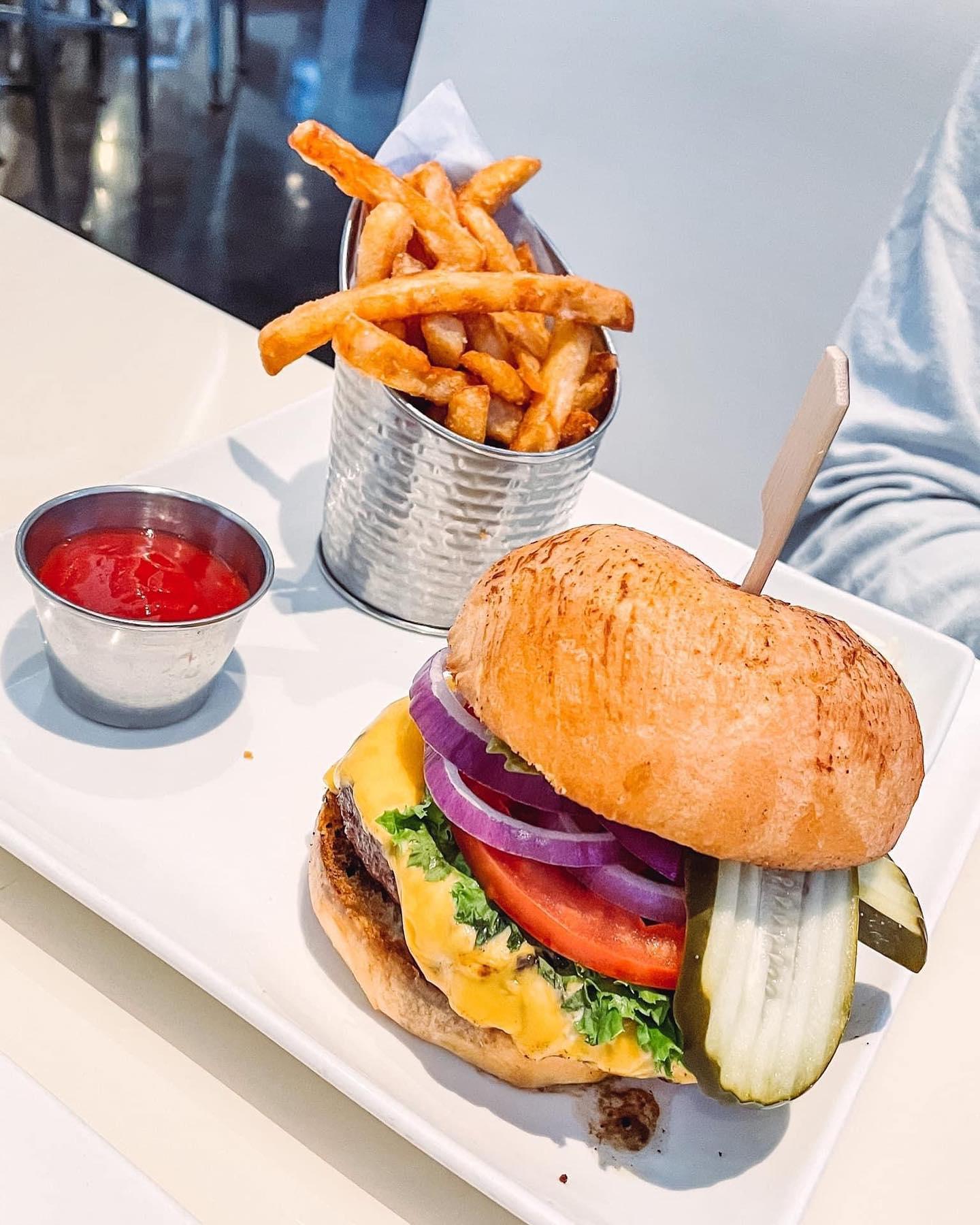 a large burger with various toppings on a white plate with fries