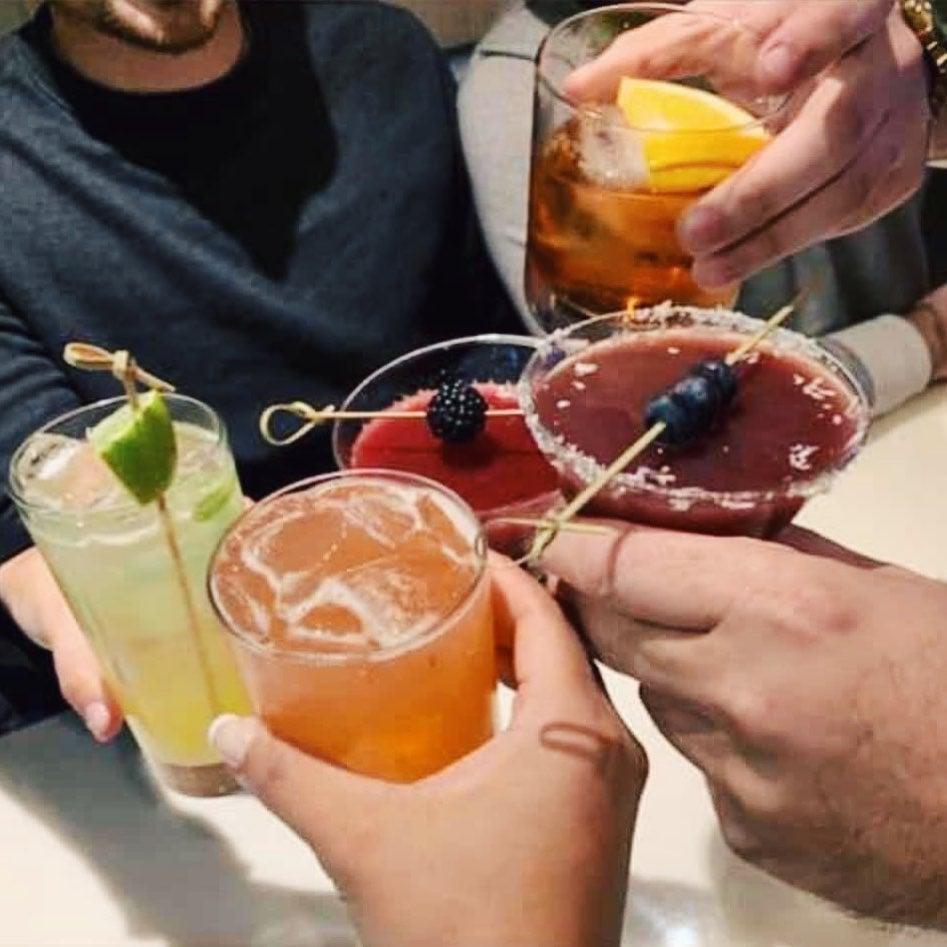 friends tapping their cocktails together in celebration