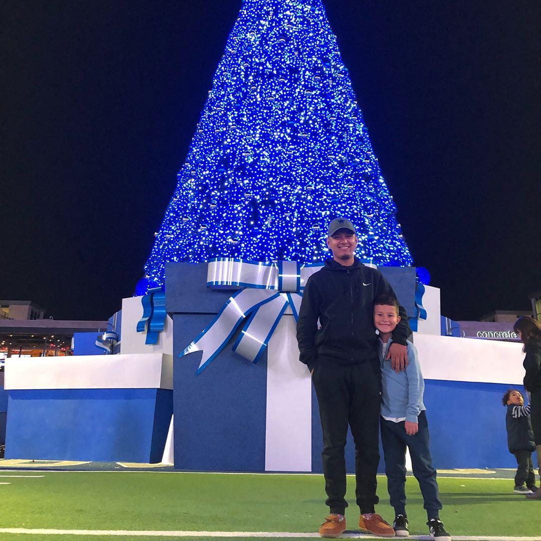 A father and son standing in front of a large blue Christmas tree