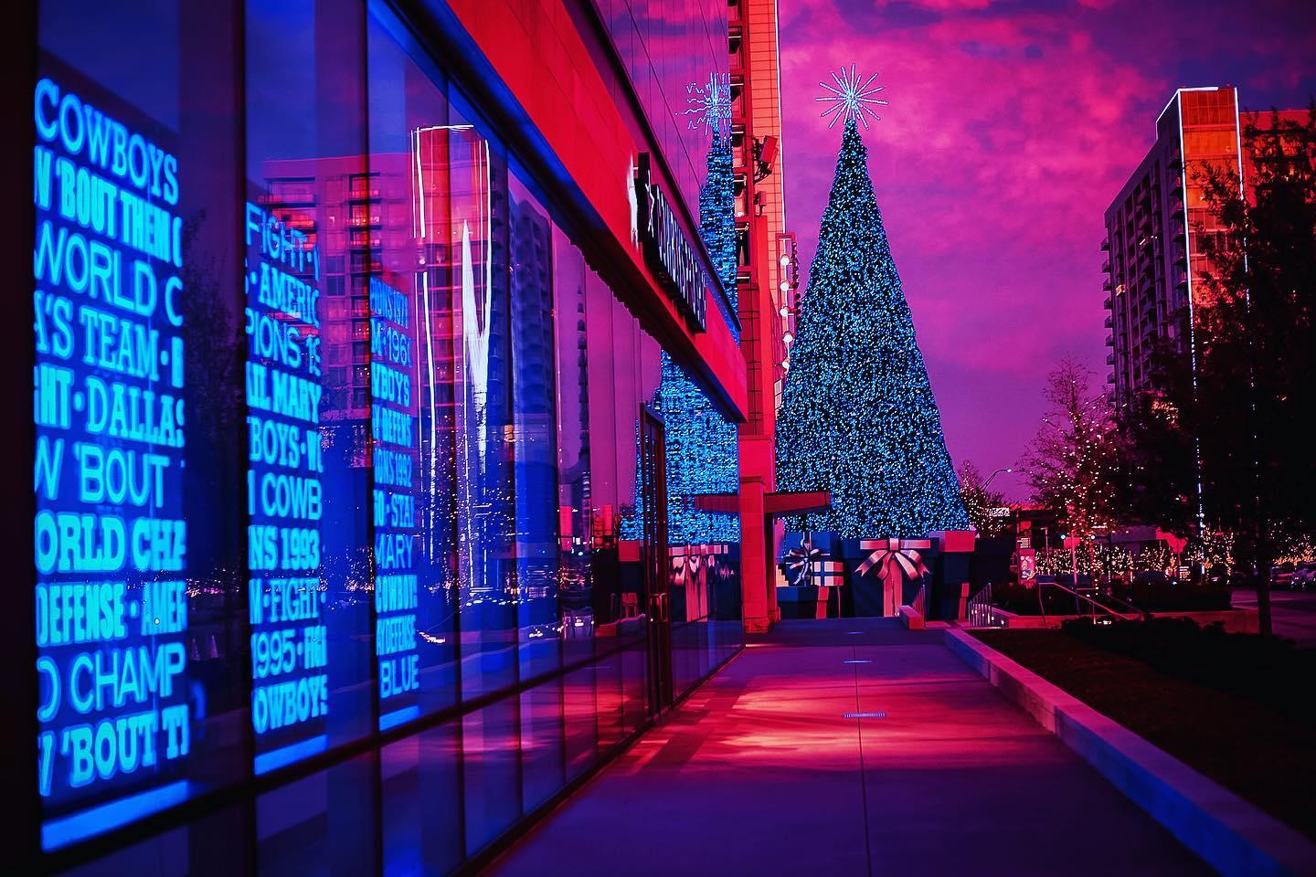 a sidewalk leading to a large Christmas Tree during a pink and purple sunset
