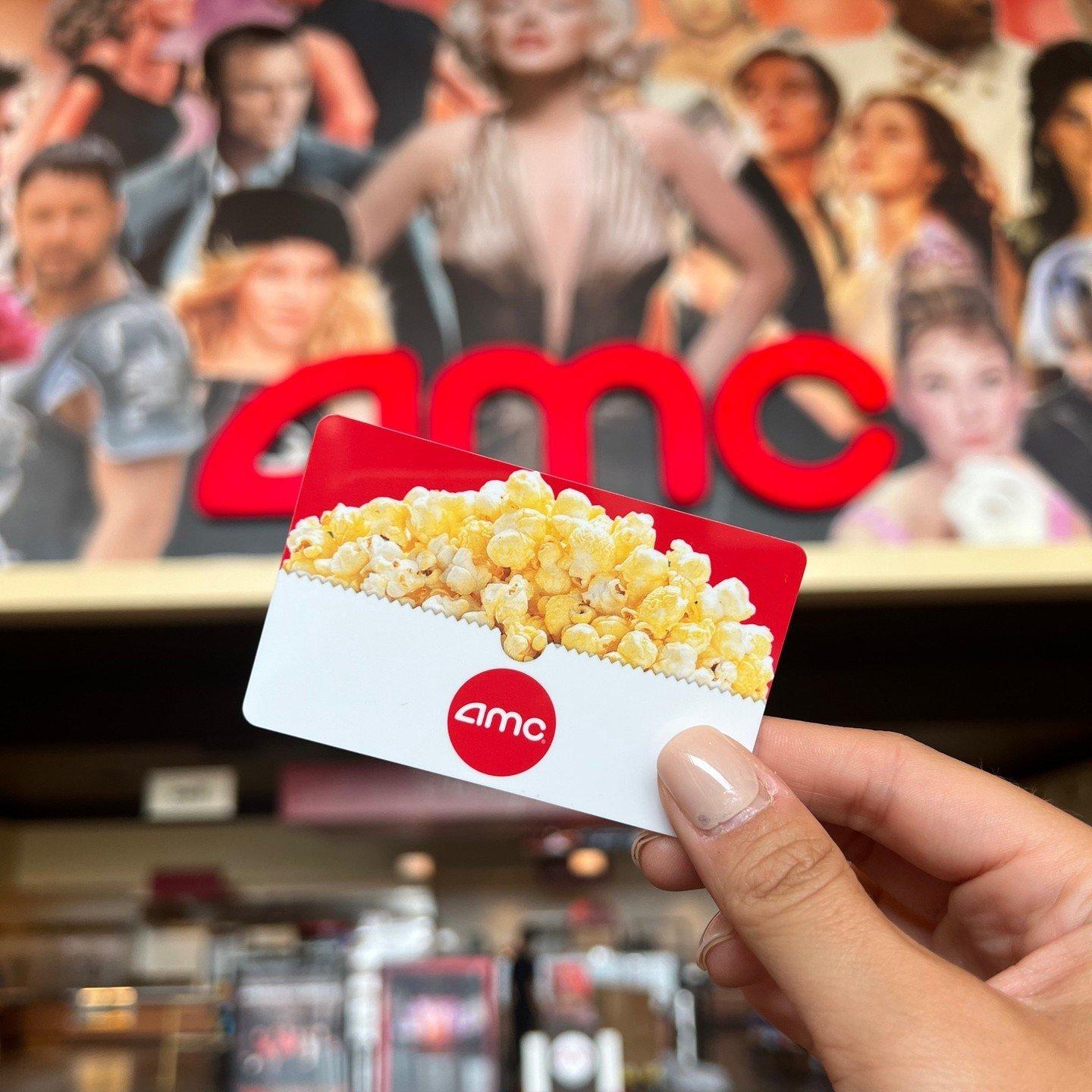 someone holding up an AMC gift card in front of the theater signage
