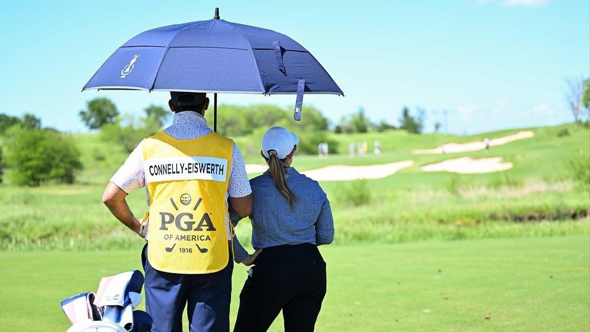 a caddy holding an umbrella over a golfer