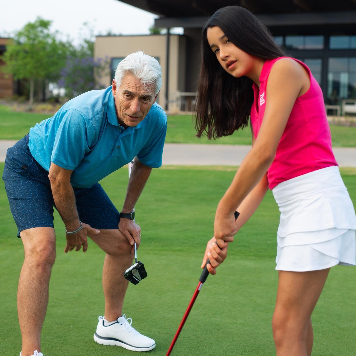 an instructor watching as his student hits the golf ball