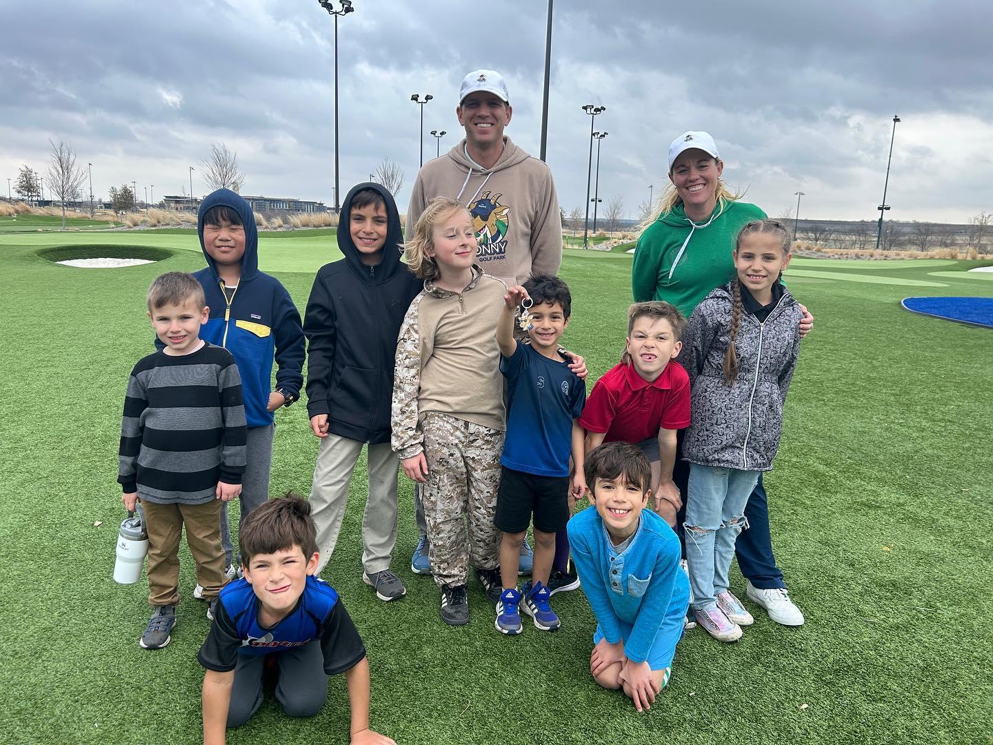 a group of children posing with their instructors on a golf course