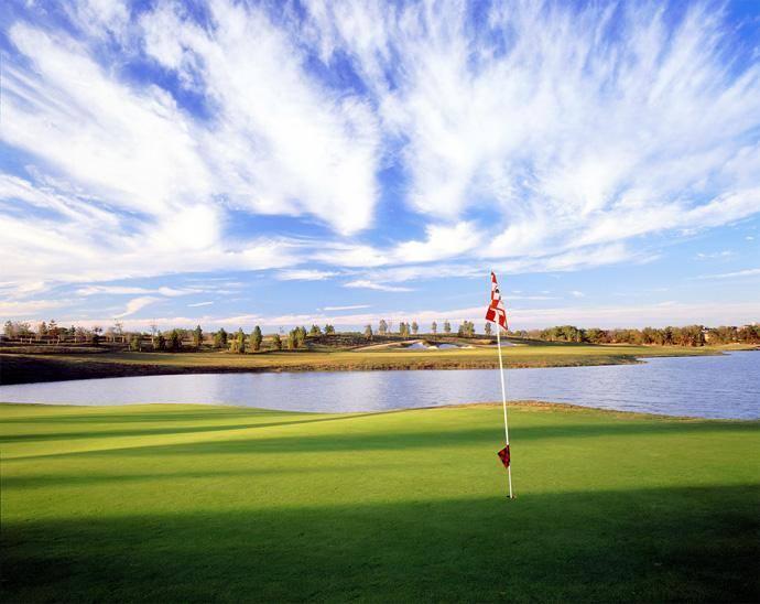 A flag indicating where the hold in on a golf course with a lake and cloudy sky in the background