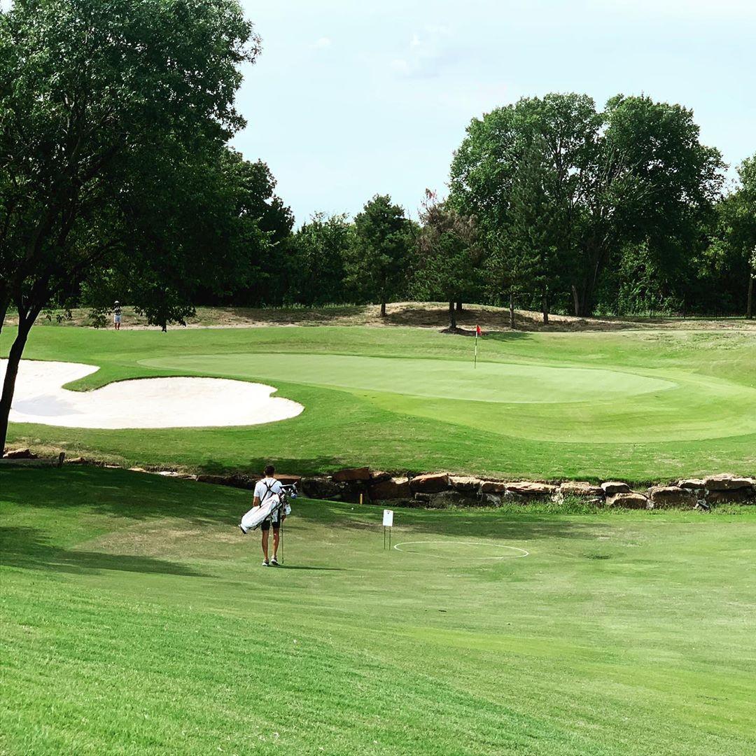 a man walking to the next hole on a golf course