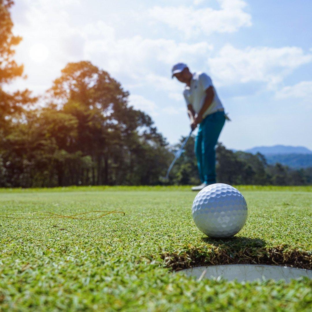 a golfer watching where their ball will land after they hit it towards the hole