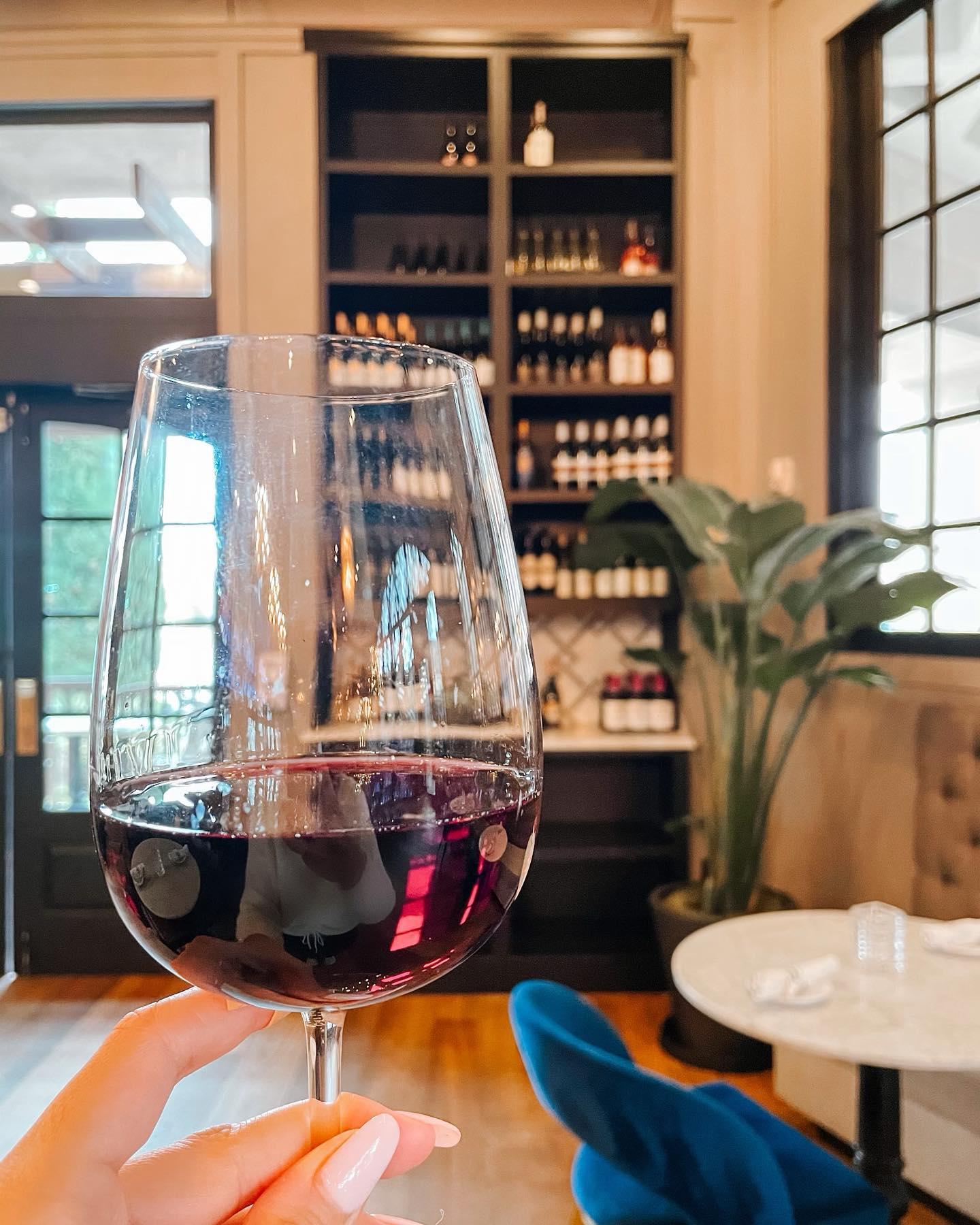 A hand holding up a glass of red wine
