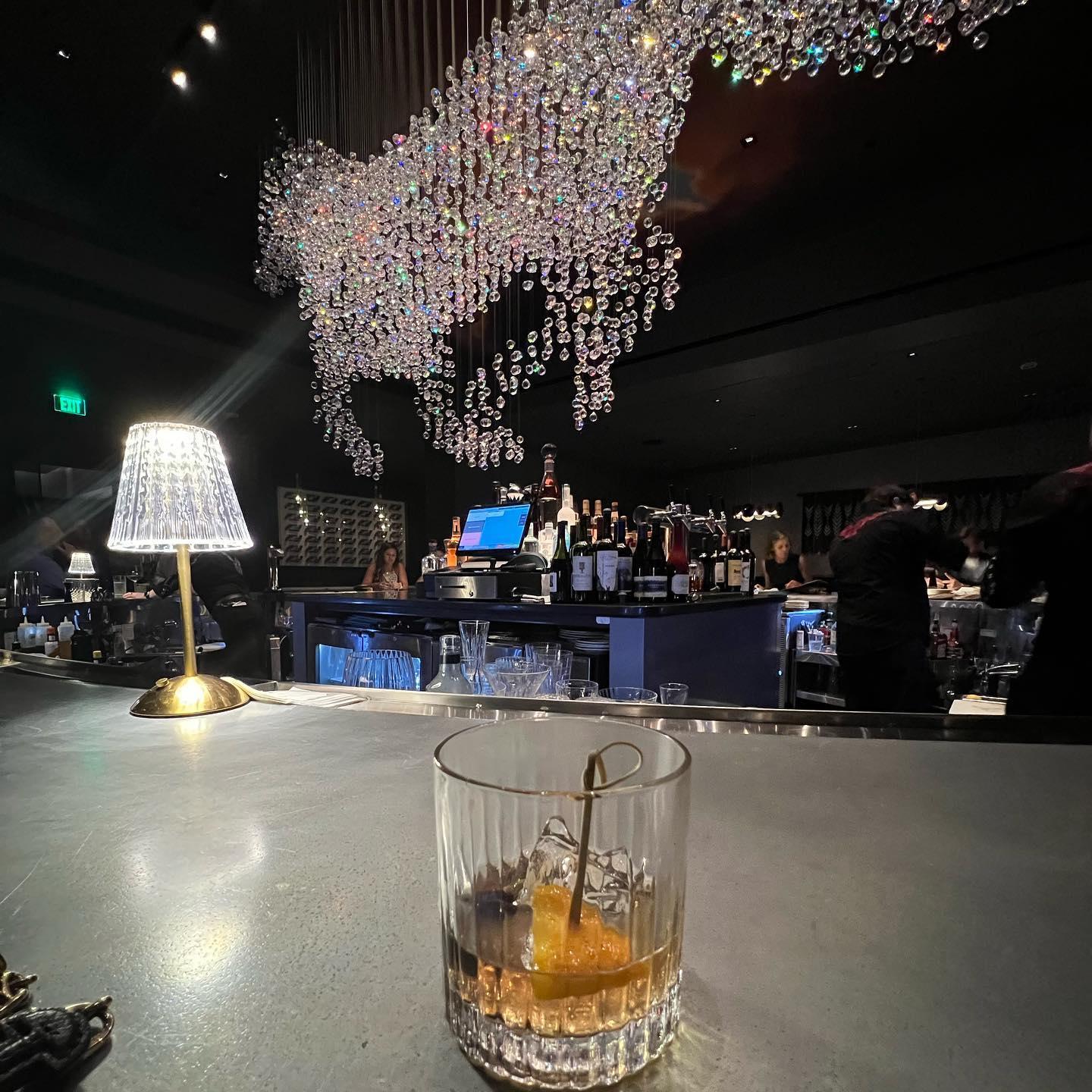 A cocktail on a bar top with a giant horse chandelier