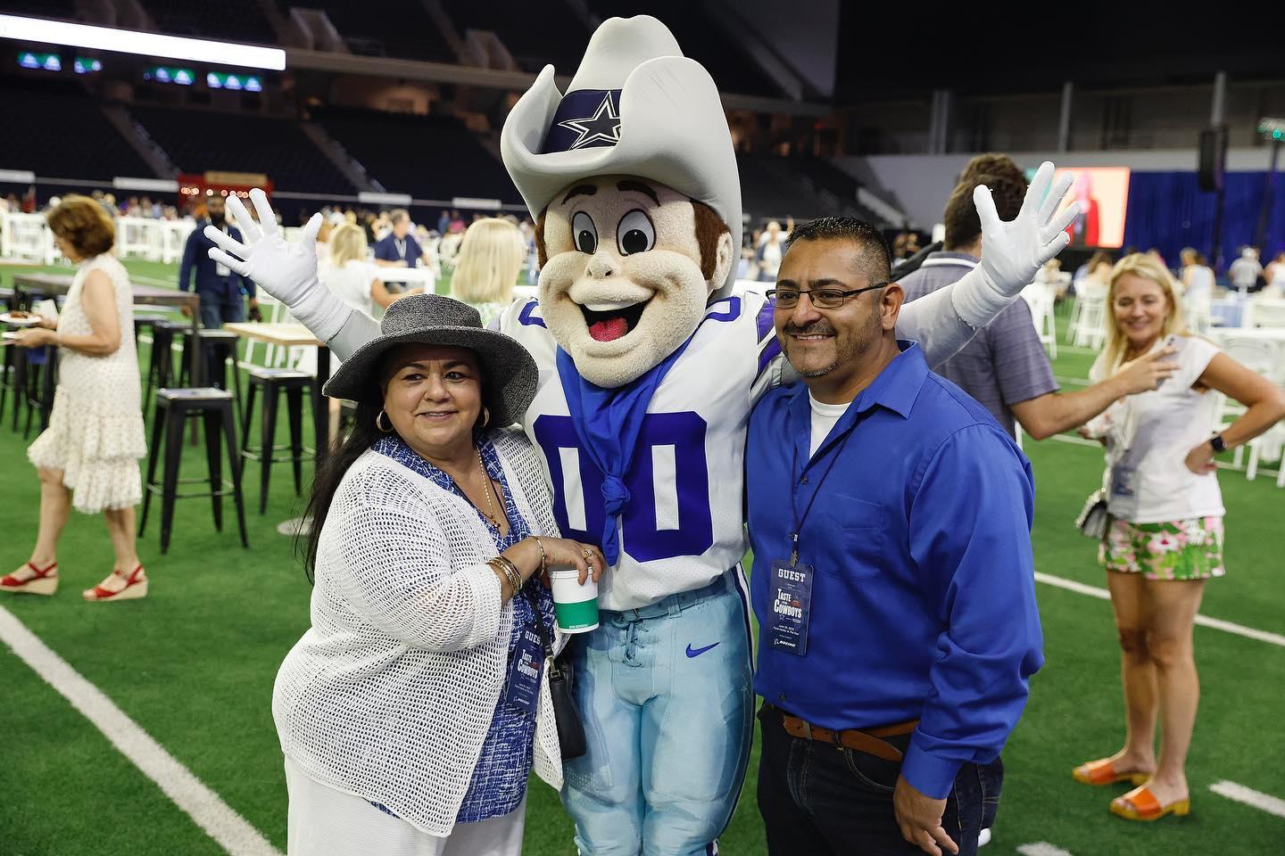 2 people posing for a photo with the Dallas Cowboys mascot
