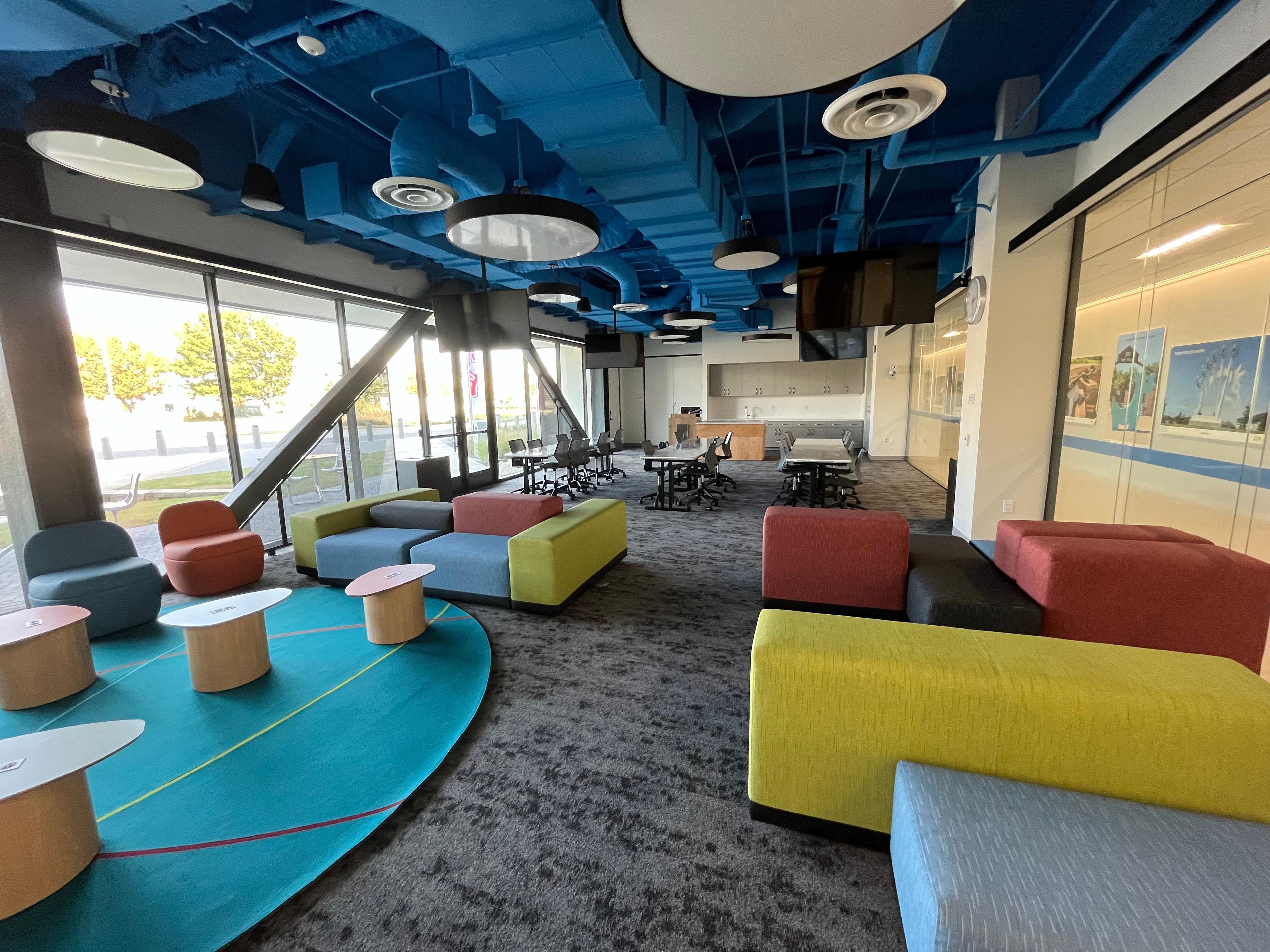 An empty colorful meeting space with tables, chairs, and sofas
