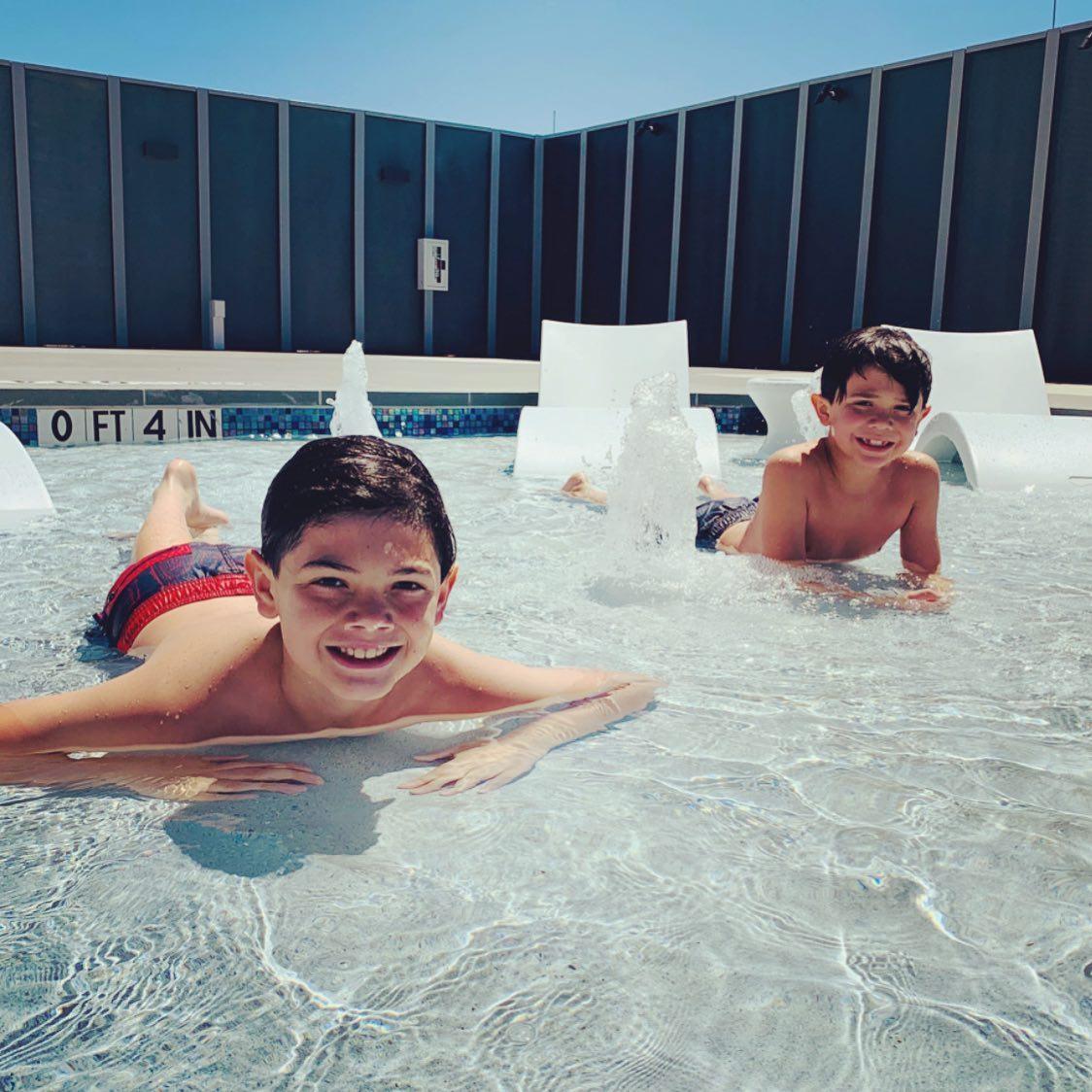 Two kids in a pool posing for a photo