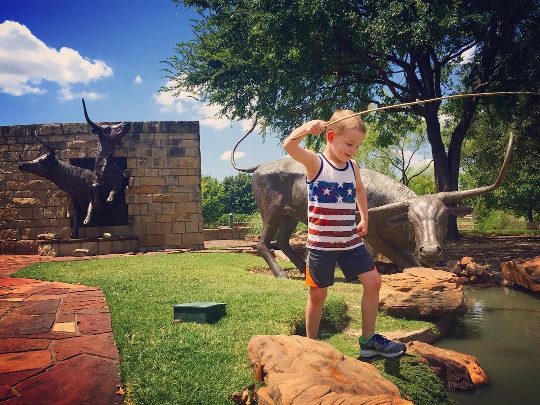 a little boy playing with a stick near a small river