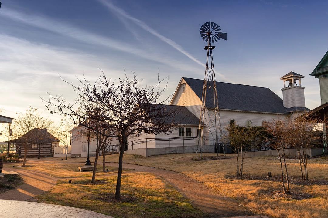 a small park with dirt pathways in front of an old church