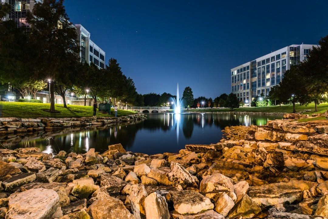 rocky shore of a lake with a large lit up fountain