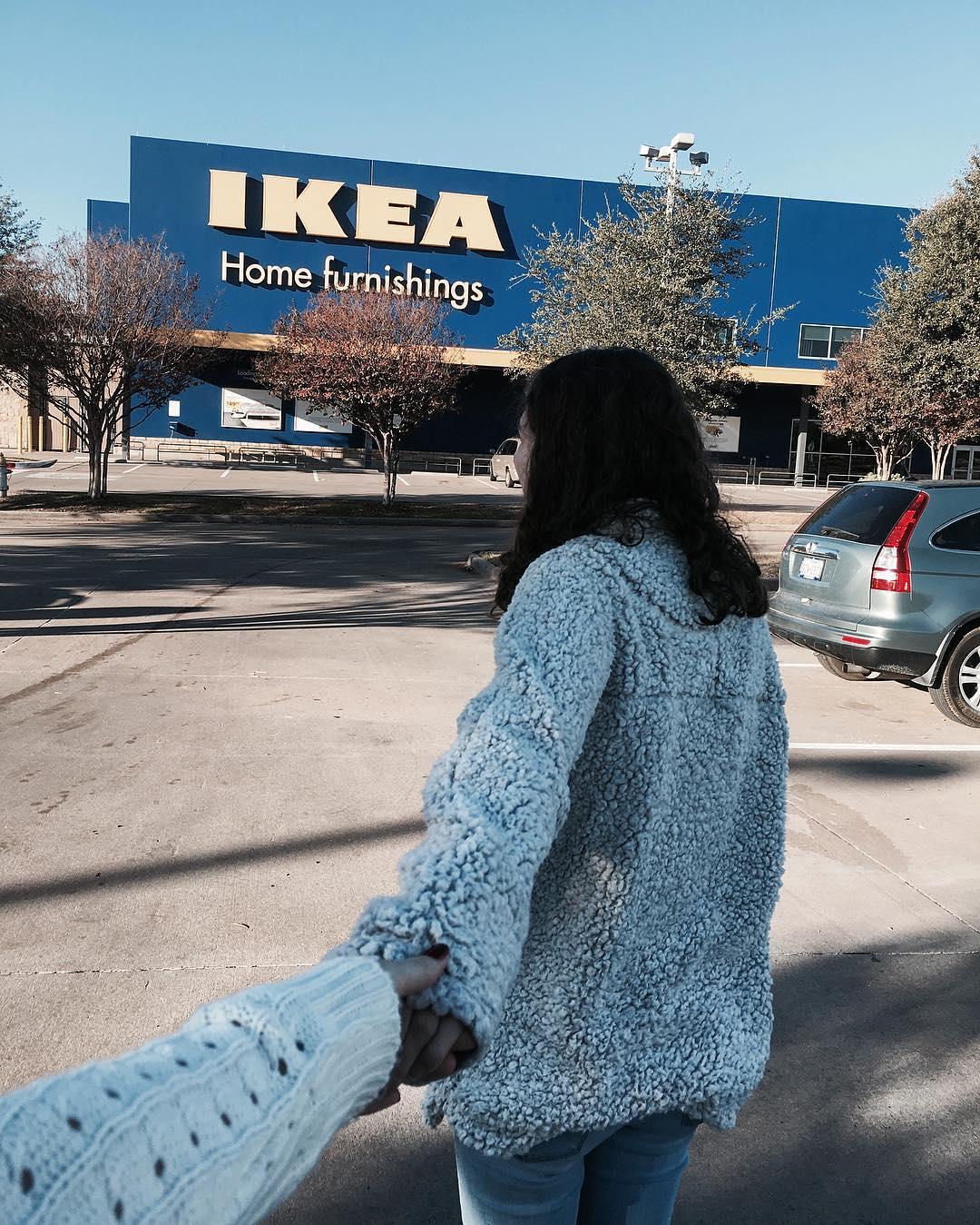 a couple holding hands while walking towards Ikea
