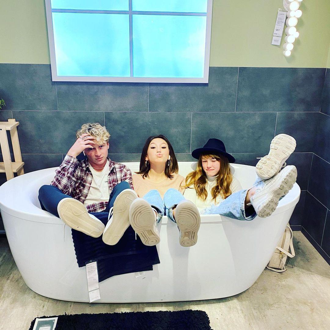 a group of friends sitting in a bathtub in an Ikea display